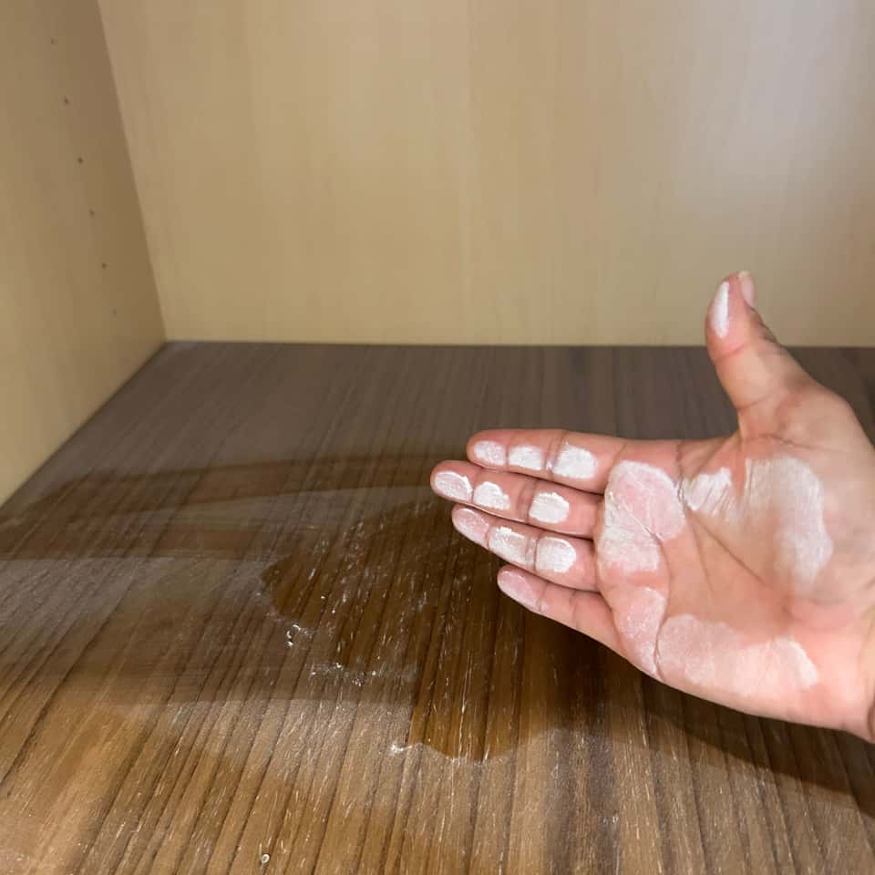 Hand checking a freshly wiped wood-grain cabinet interior — Coastal Clean & Care LLC