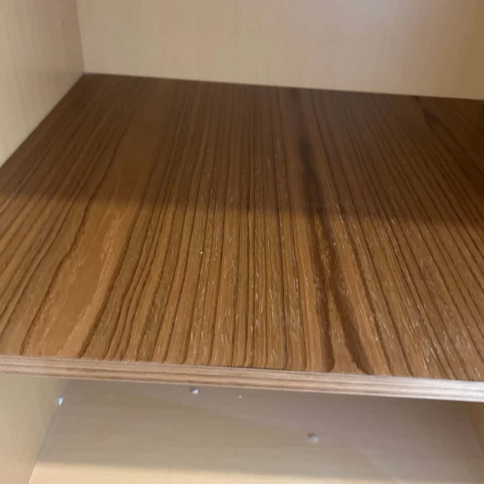 Empty wood-grain cabinet shelf wiped clean — Coastal Clean & Care LLC
