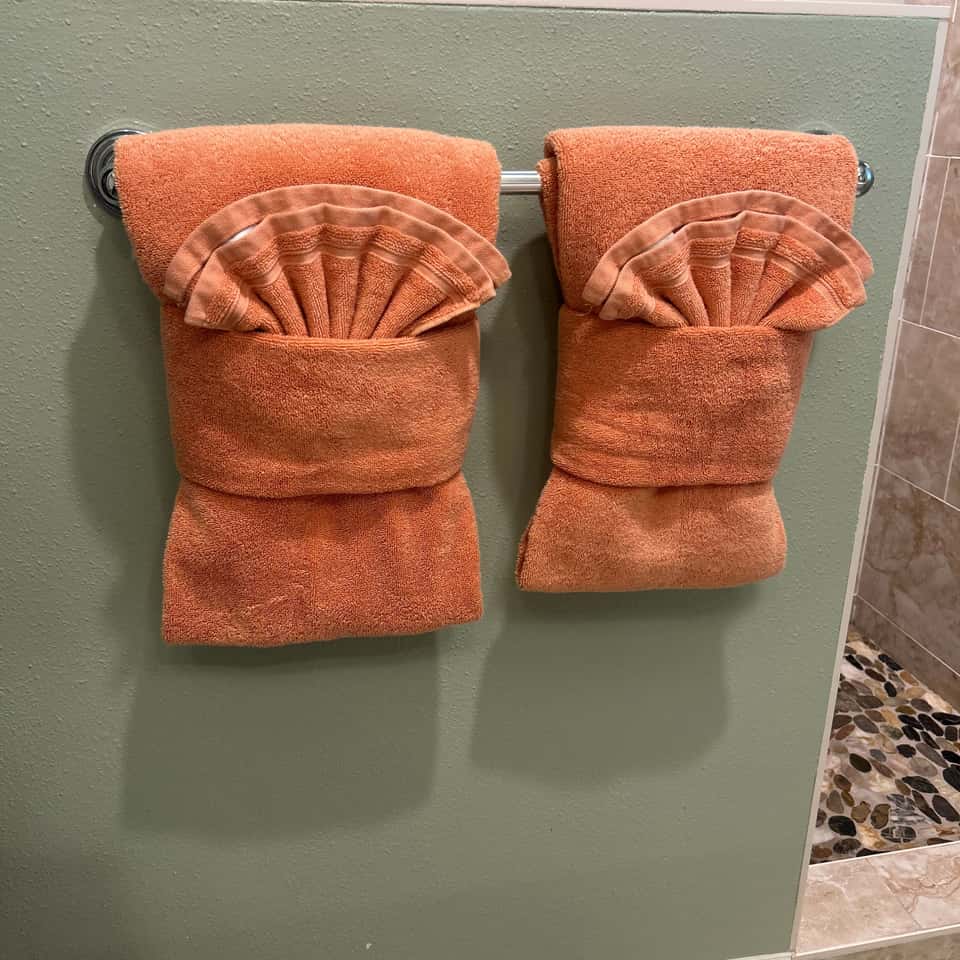 Two orange towels folded into fans on a bathroom towel rail — Coastal Clean & Care LLC